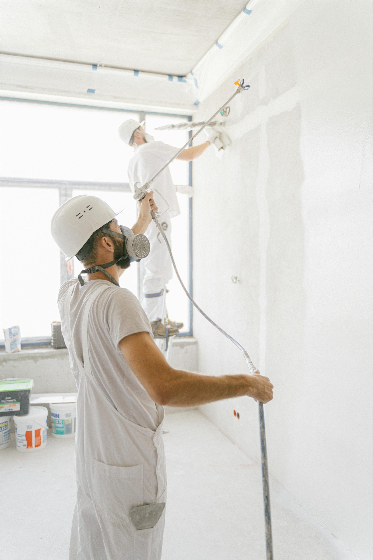 Deux peintres appliquent une finition sur un mur intérieur en chantier
